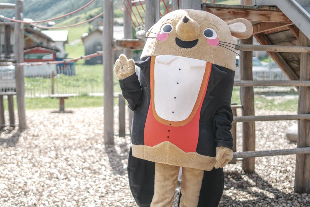 Maskottchen Herr Gorfion winkt auf dem Spielplatz