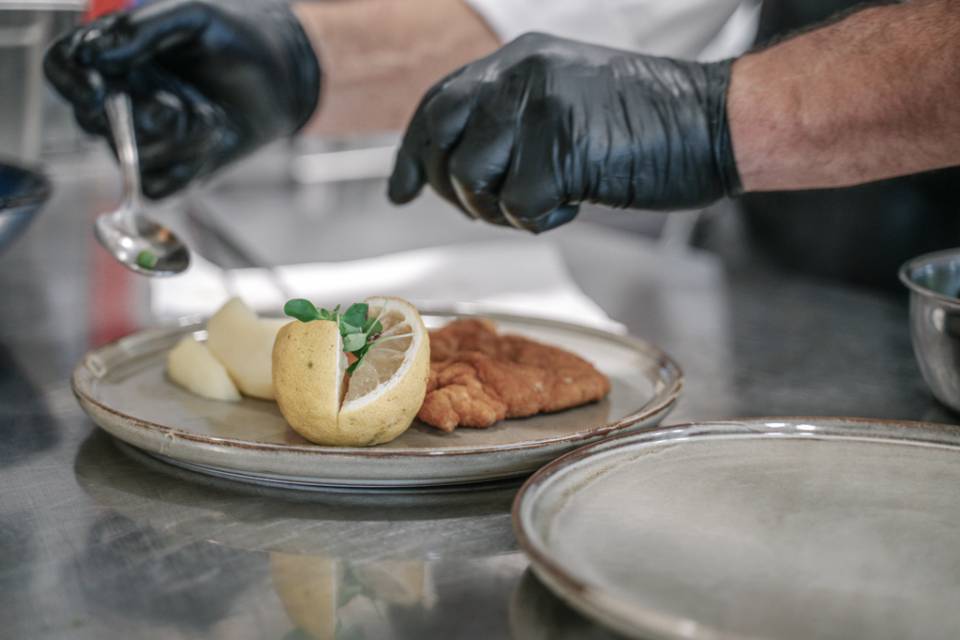 Koch richtet paniertes Schnitzel mit Zitrone an