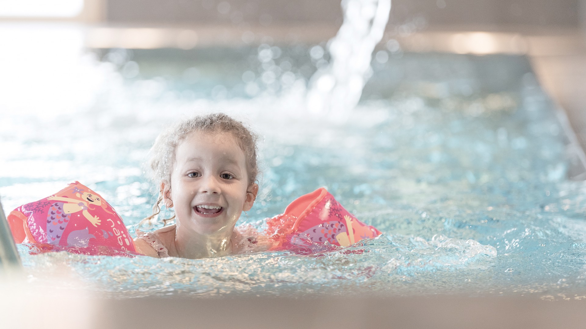 Mädchen mit Schwimmflügeln im Hallenbad