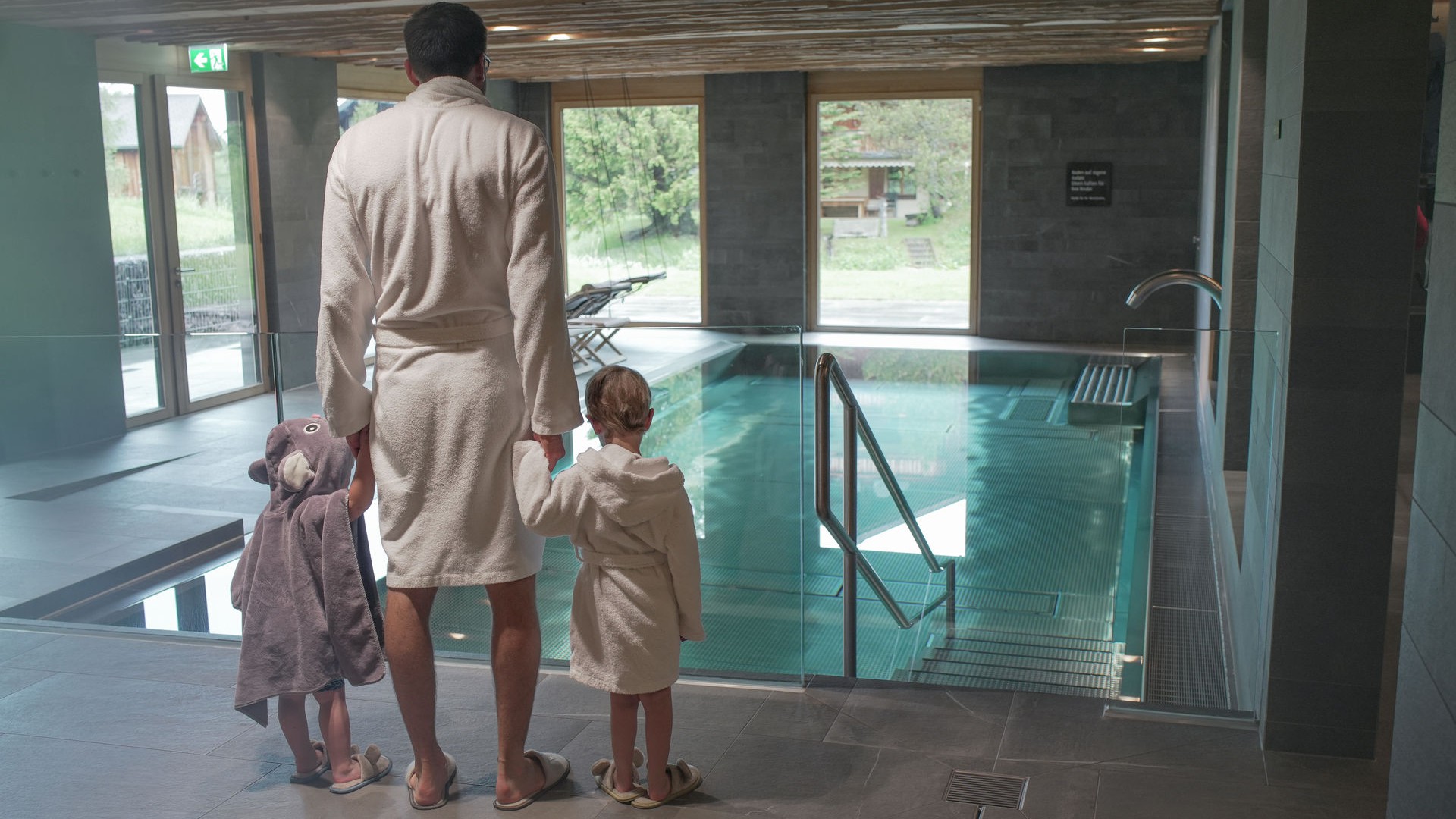 Vater mit Kindern im Bademantel vor dem Pool im Familienhotel Gorfion